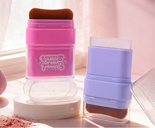 Multicolor portable blush powder containers with built‑in makeup brushes on soft pastel table background